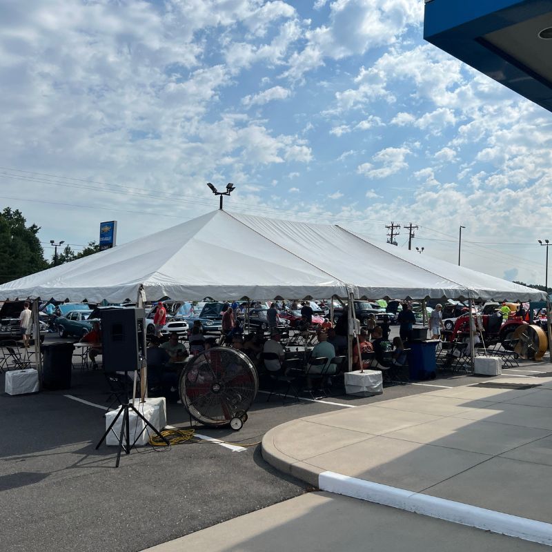 Outdoor market under a large white tent with bicycles, vendors, and tables on a sunny day