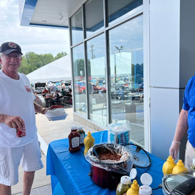 Two people beside a blue table with food and condiments outside a glass-front store