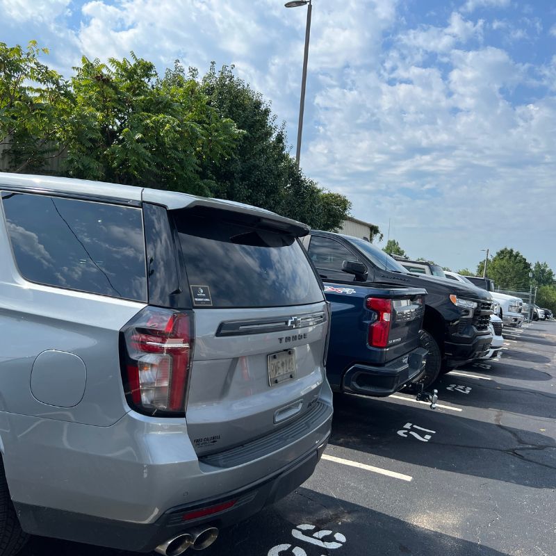 Row of parked SUVs in an outdoor parking lot under a bright, partly cloudy sky