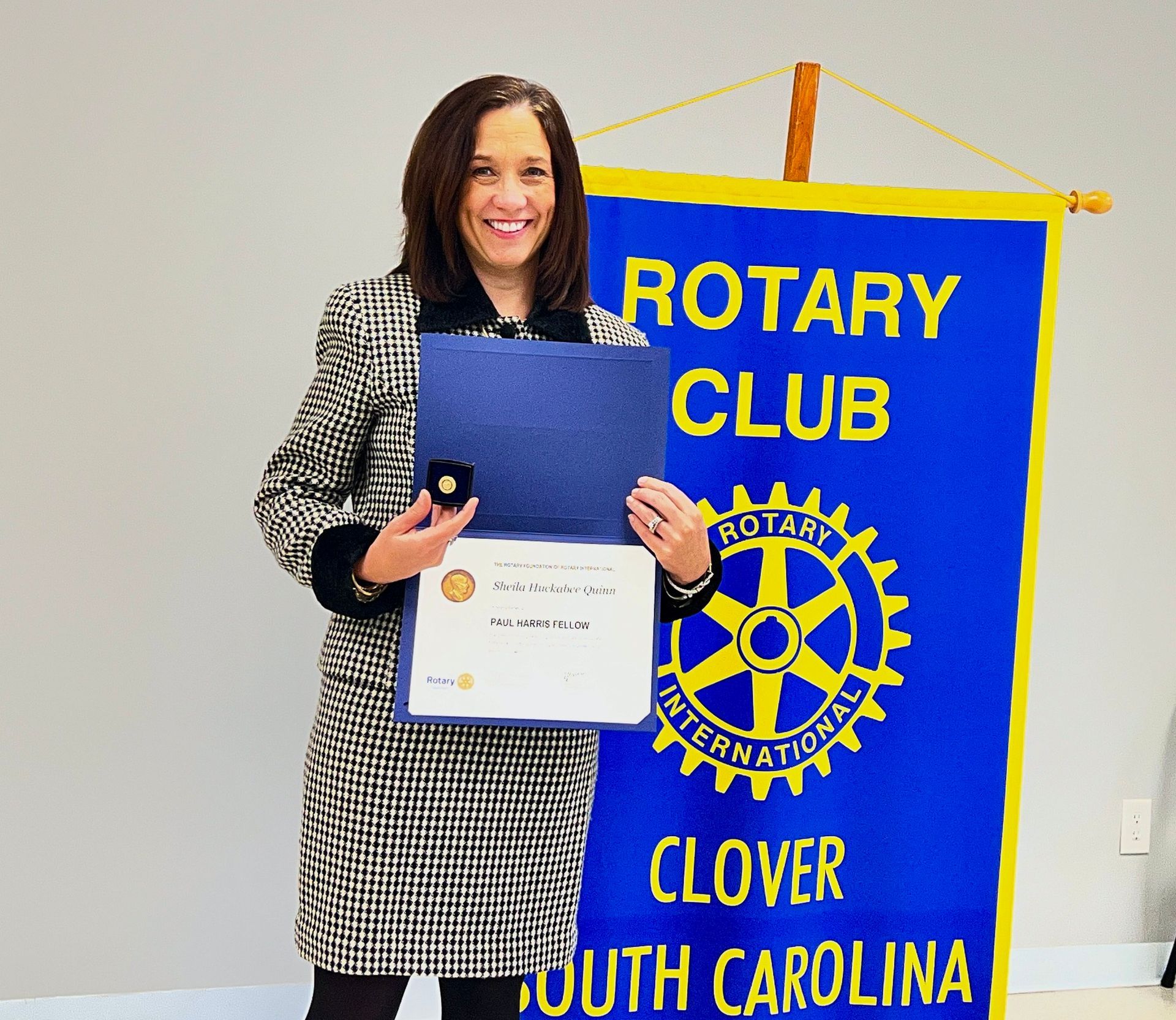 Woman holding certificate in front of a blue Rotary Club banner in Clover, South Carolina