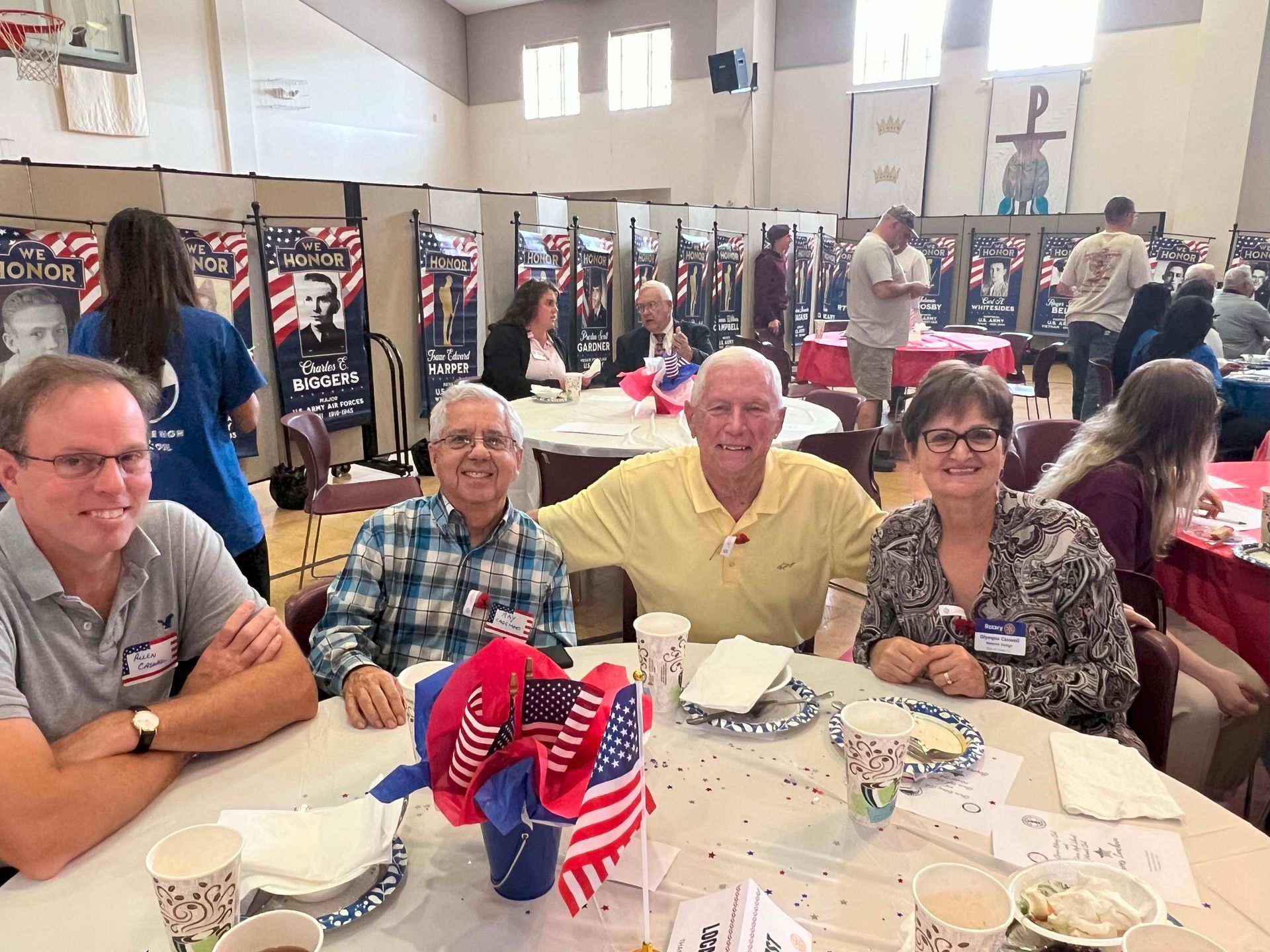 Group seated at a banquet table with red, white, and blue decor in a hall