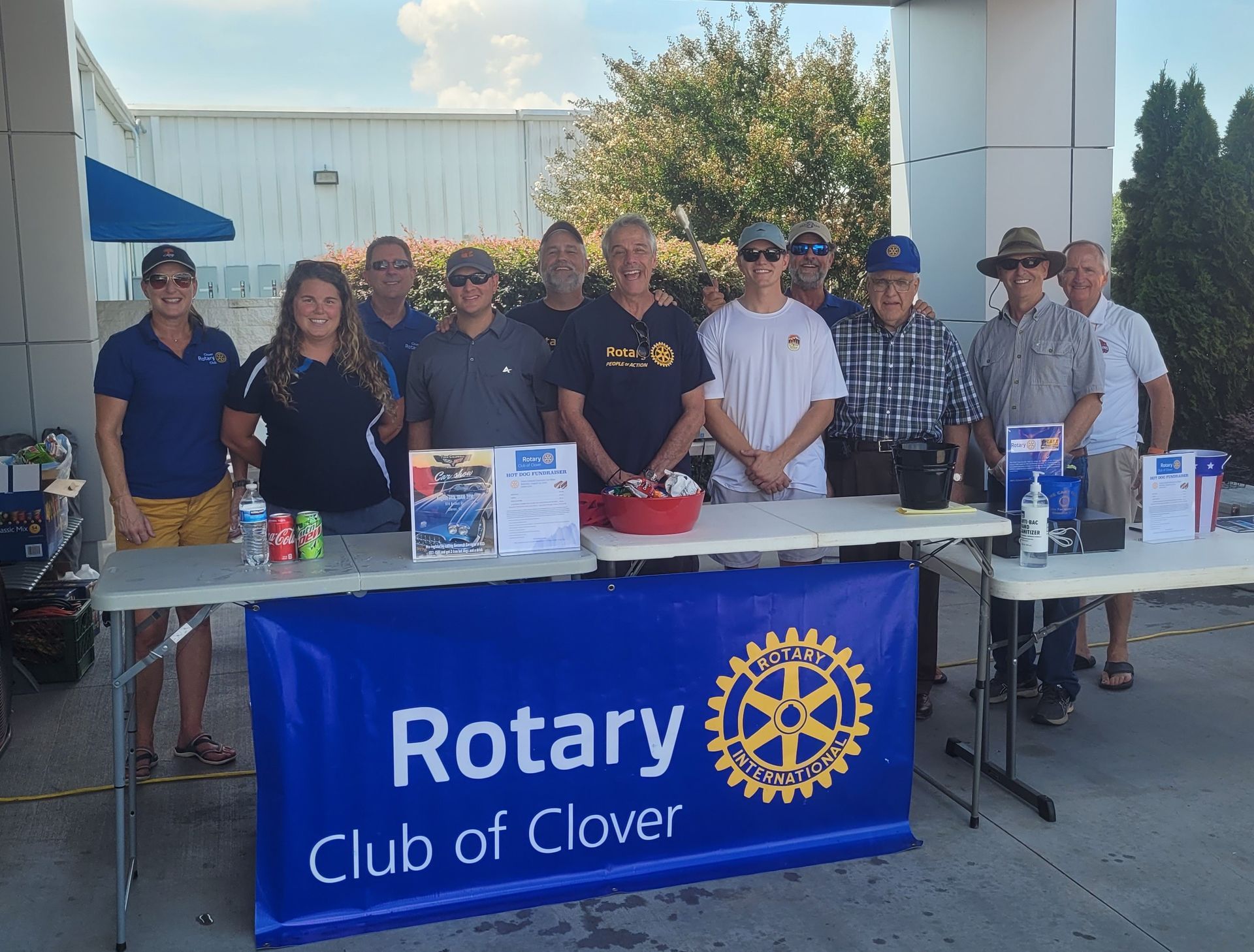 Rotary Club of Clover volunteers standing behind a table with a blue club banner outdoors