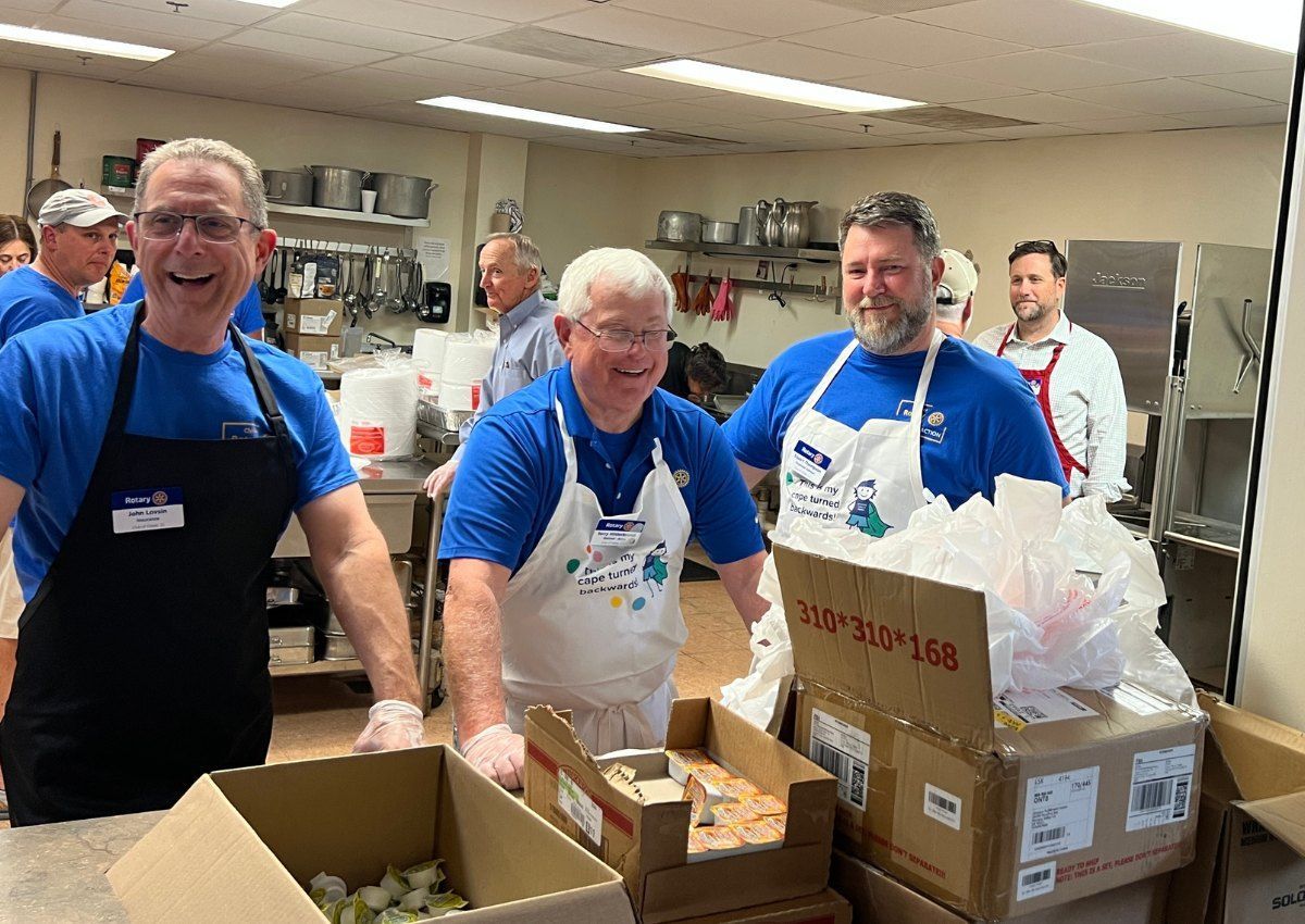 Volunteers in blue shirts packing food boxes in a community kitchen