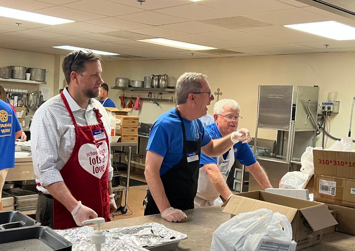 Volunteers in aprons packing food boxes in a community kitchen