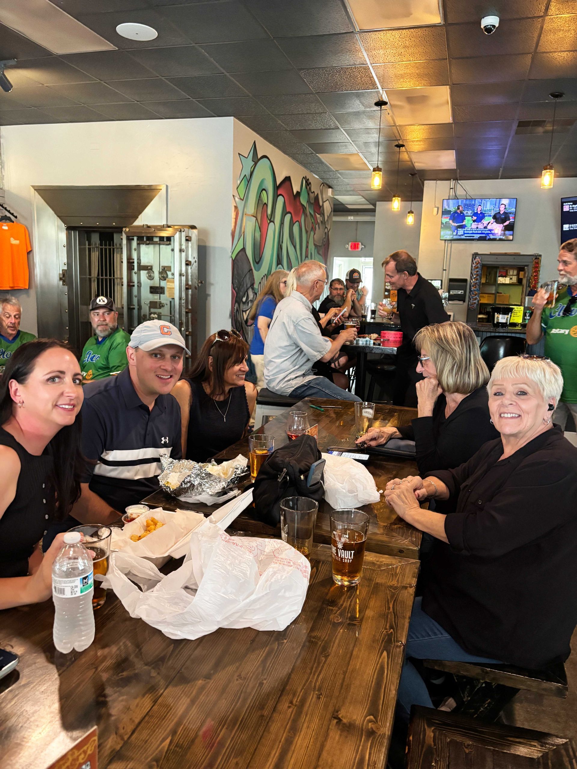 Group seated at a restaurant table, smiling and chatting over drinks and food in a casual dining setting