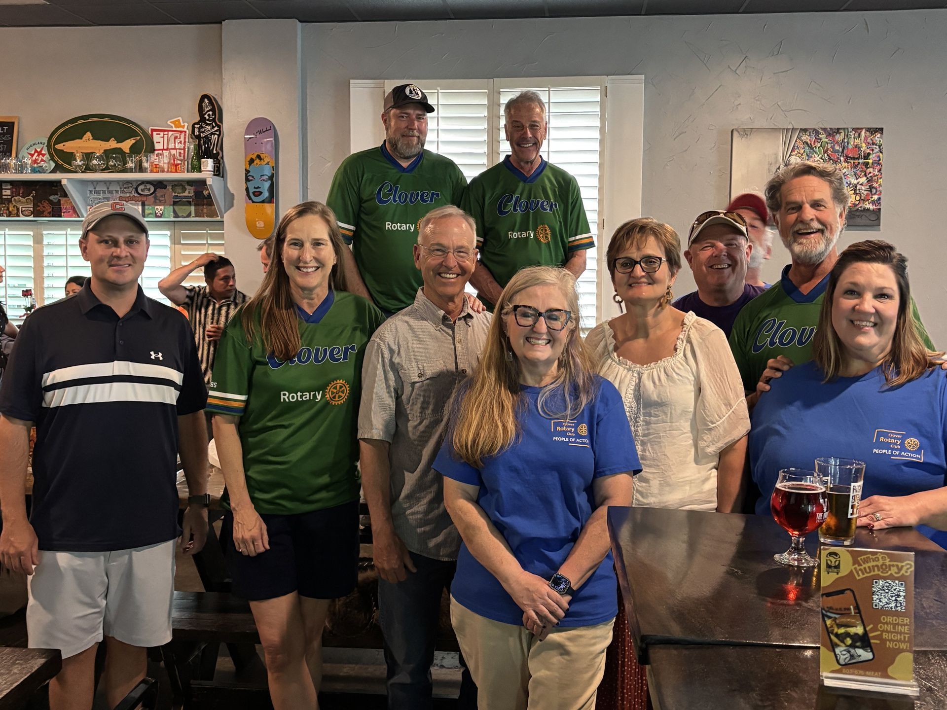A group of people posing together in a bright kitchen, smiling at the camera.