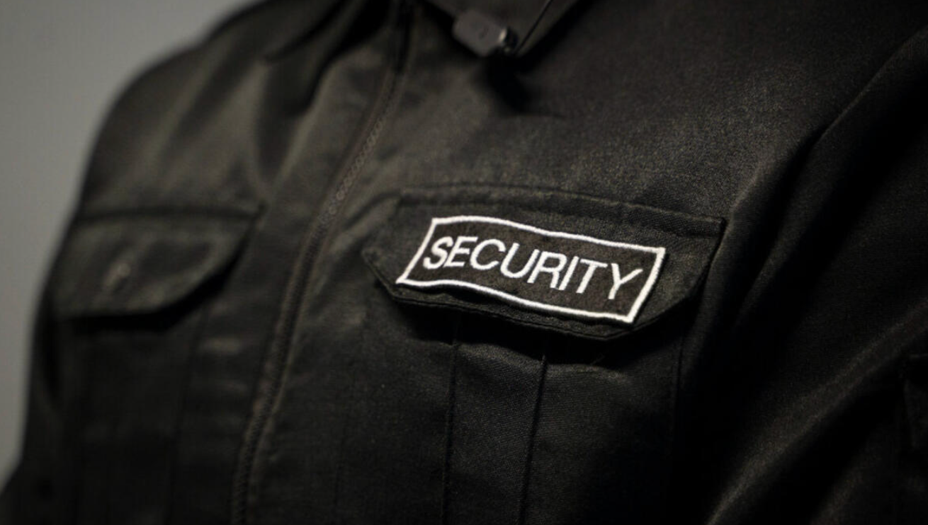 Black security uniform with a white “SECURITY” patch on the chest