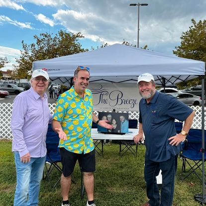 Three men are posing for a picture in front of a tent.