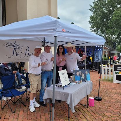A group of people standing under a tent with a sign that says the bar
