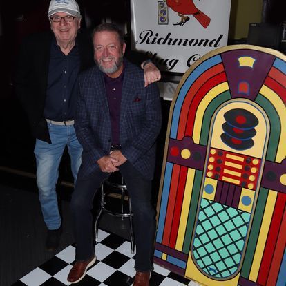 Two men standing next to a jukebox that says richmond