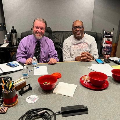 Two men are sitting at a table with bowls of food.