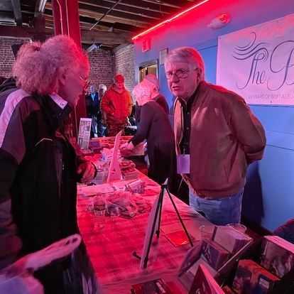 A group of people are standing around a table in front of a sign that says the f.