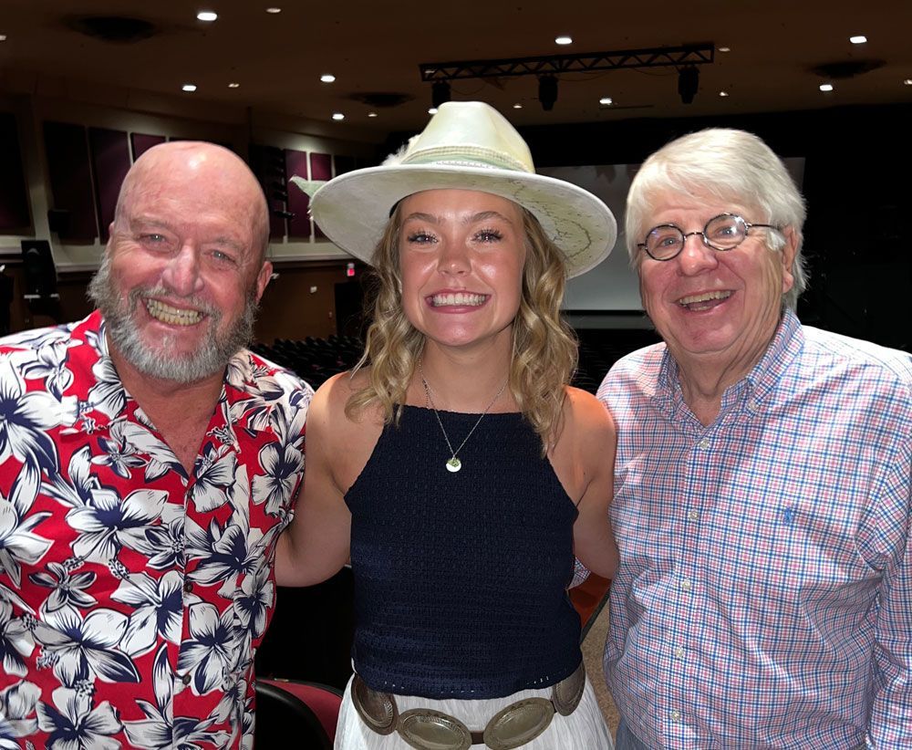A woman in a hat is posing for a picture with two men