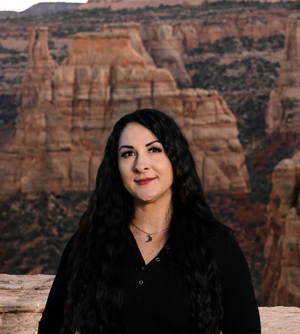 Woman in a black shirt posing before a red rock canyon backdrop.