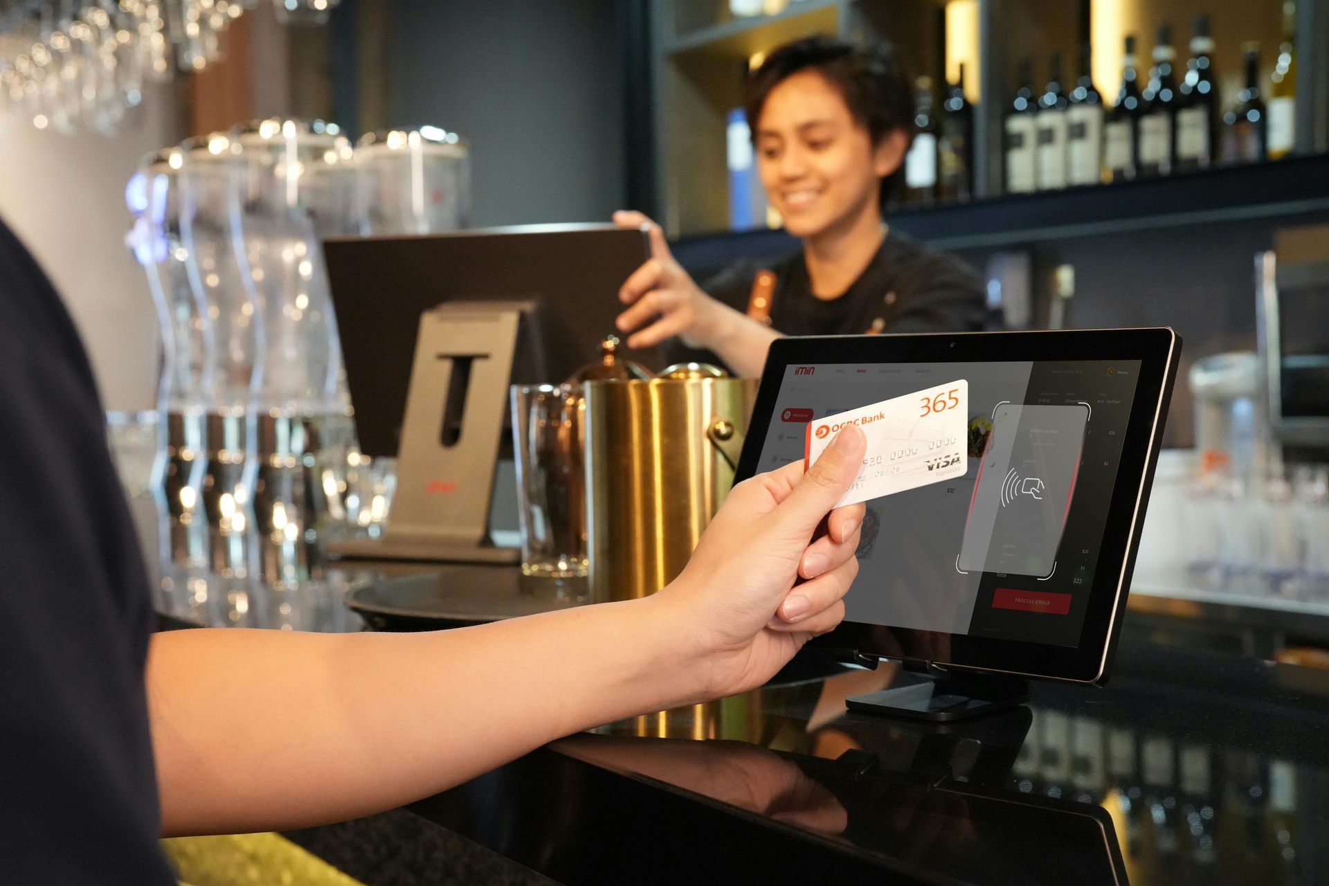 Customer pays at a café counter with a card while a barista smiles behind the register.