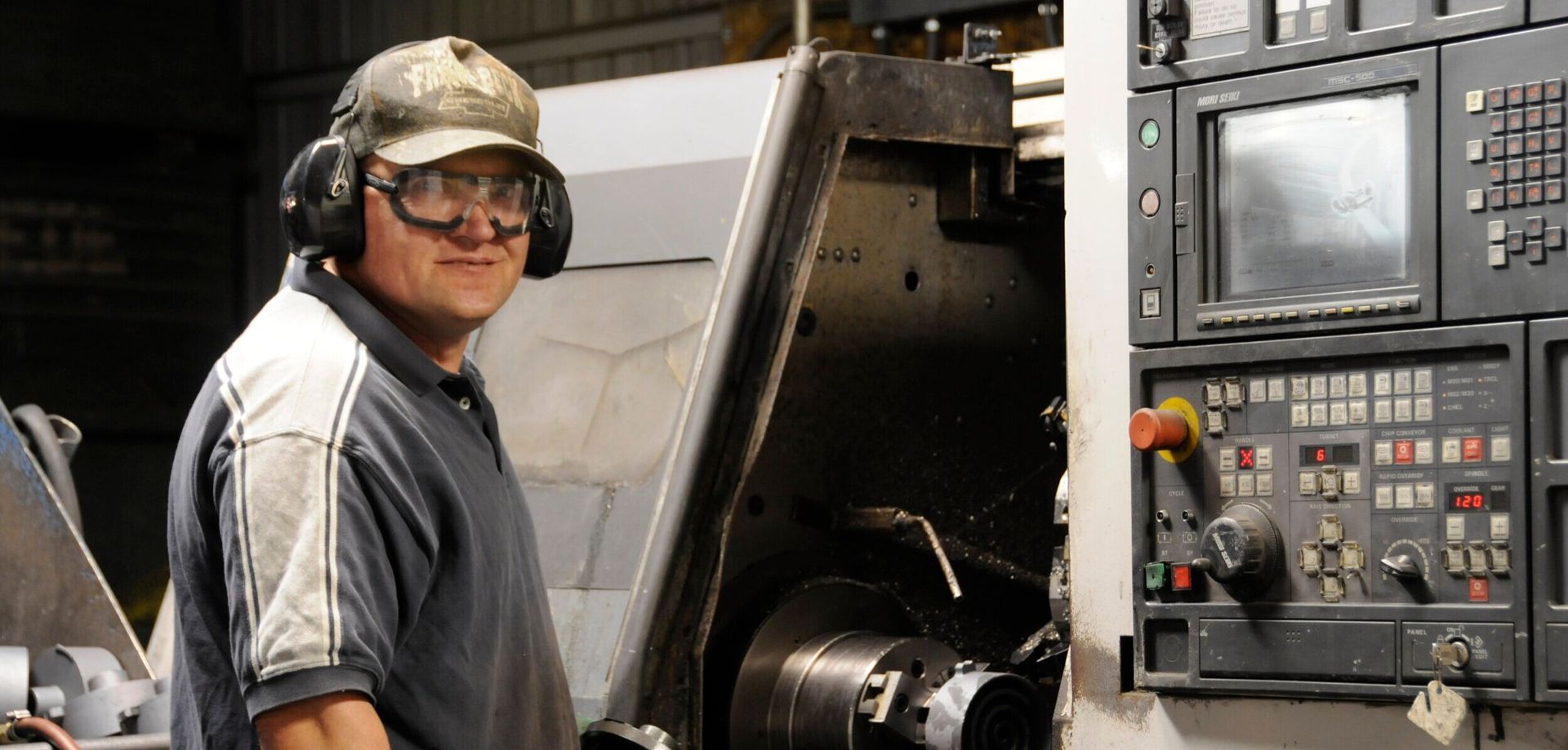 Man with headphones operating CNC machine.