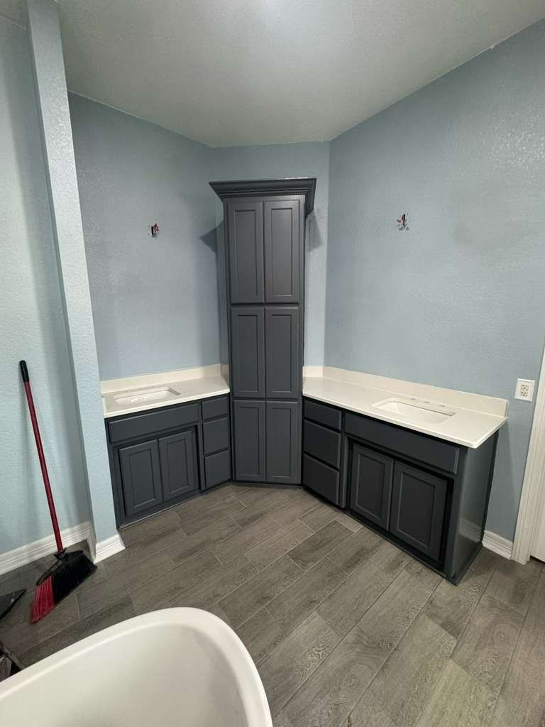 Small gray laundry room with dark cabinets, countertop, and a utility sink in the foreground.