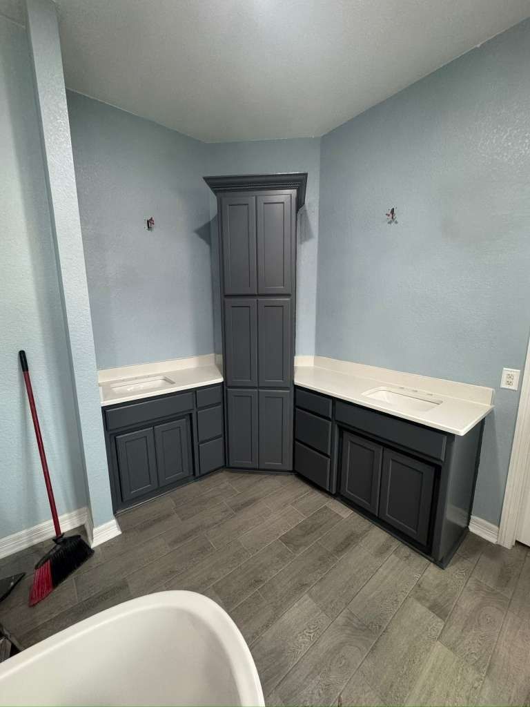 Small laundry room with gray cabinets, white countertops, and light blue walls.
