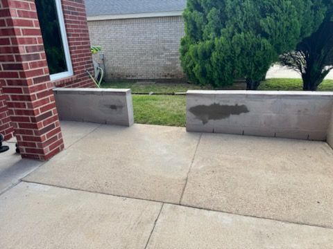 Front porch with brick columns, concrete walkway, and low retaining walls leading to a grassy yard.
