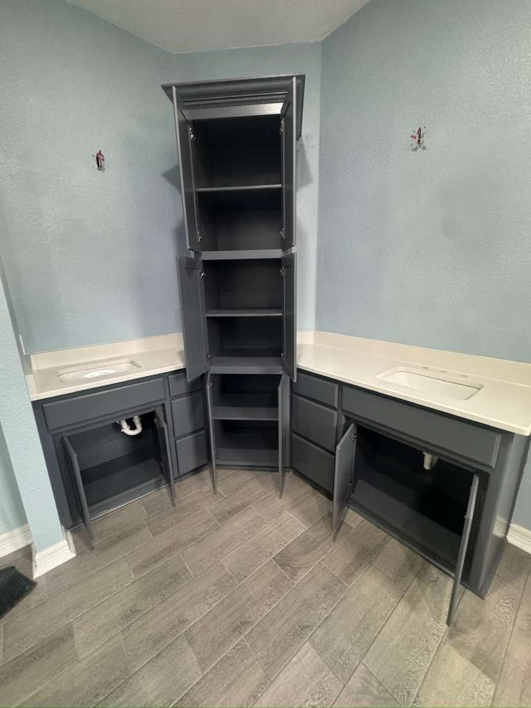Small corner home office with built-in desks, shelves, and gray walls