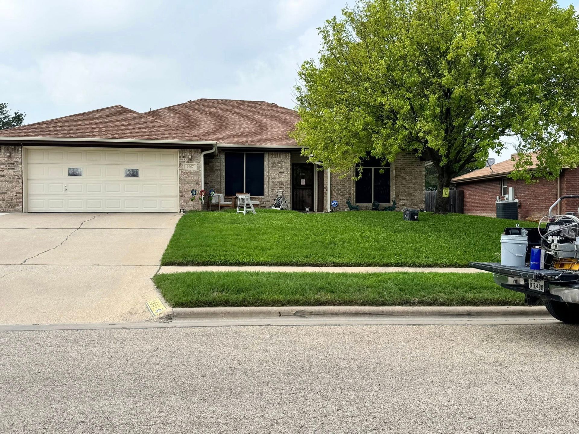 Suburban house with two-car garage, green lawn, and a pickup truck parked at the curb