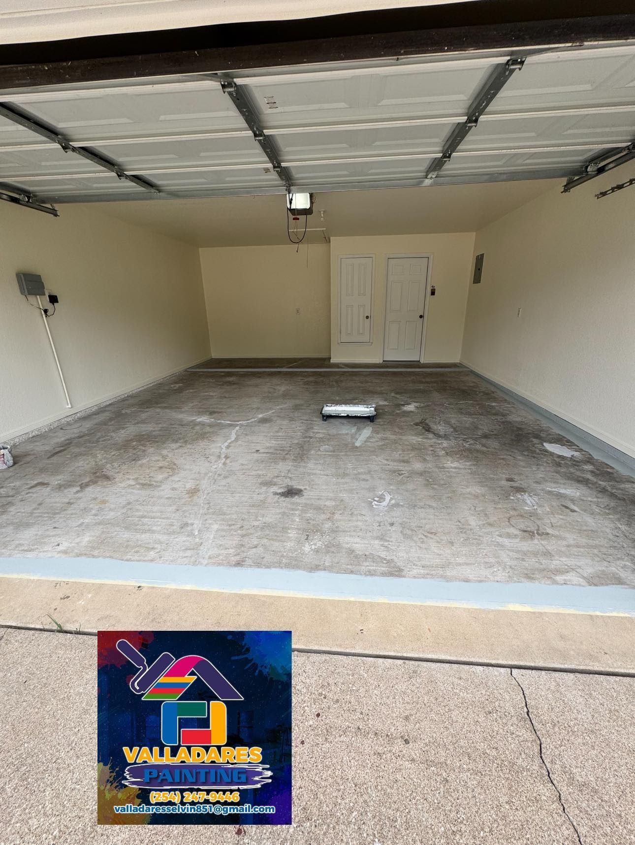 Empty residential garage with concrete floor, white walls, and closed double door at the back.