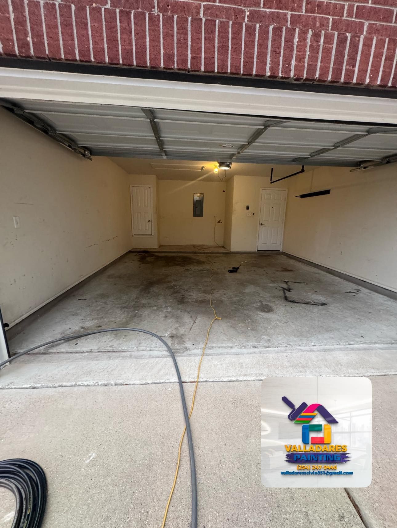 Empty two-car garage with beige walls, concrete floor, and an open ceiling door.