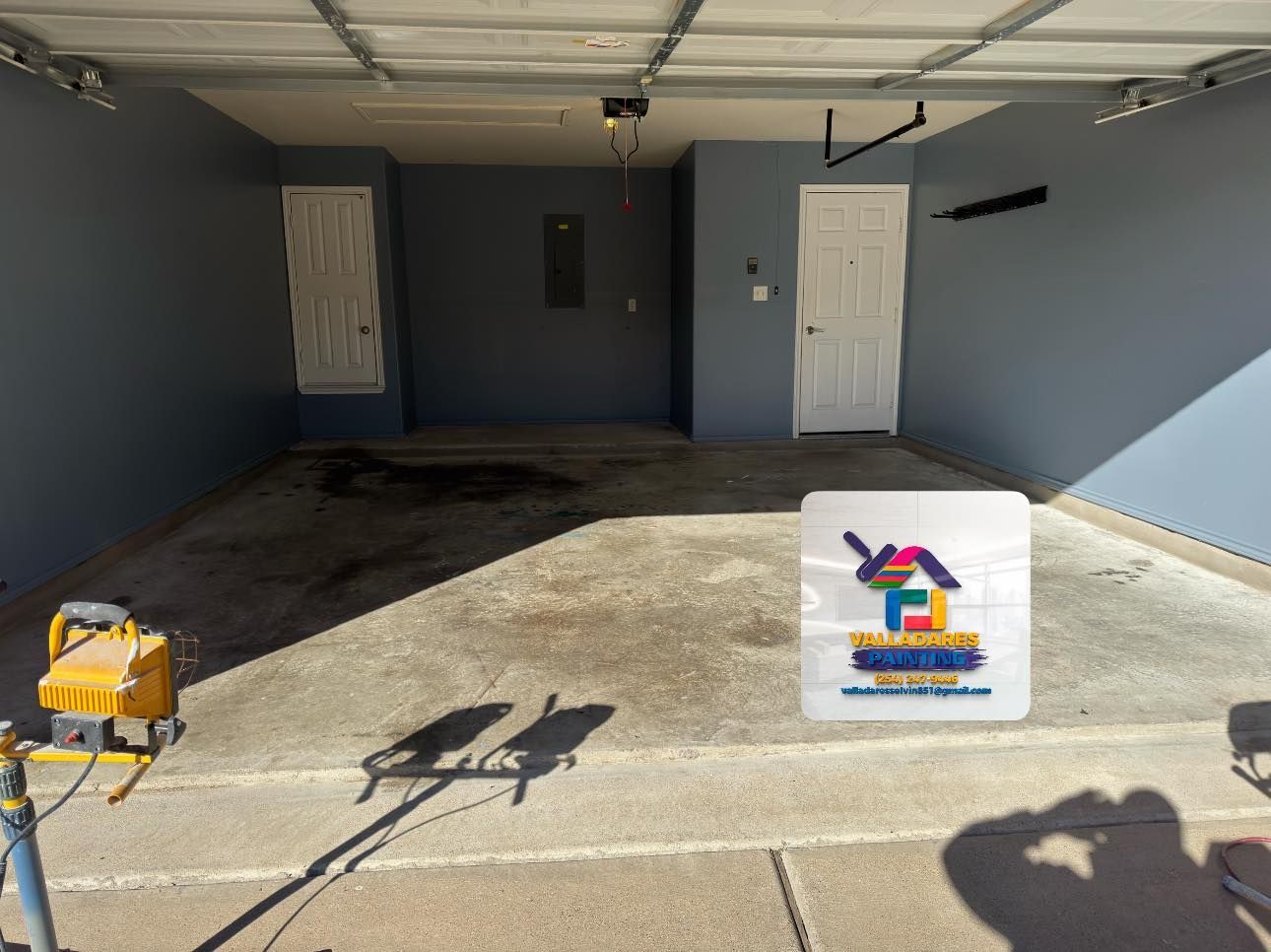 Empty garage with open door, concrete floor, and a small sign near the entrance.