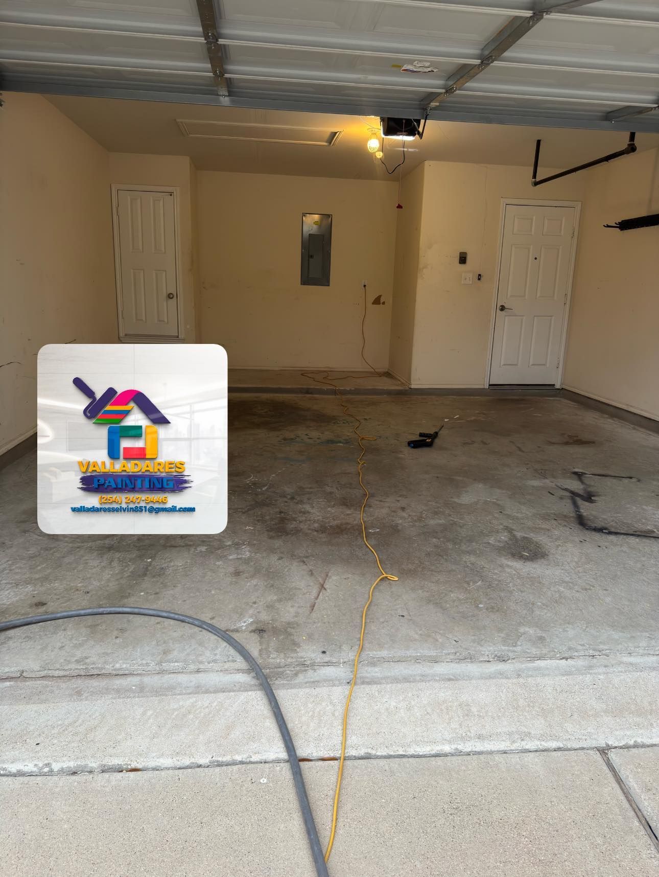 Empty garage interior with beige walls, white doors, and a concrete floor.
