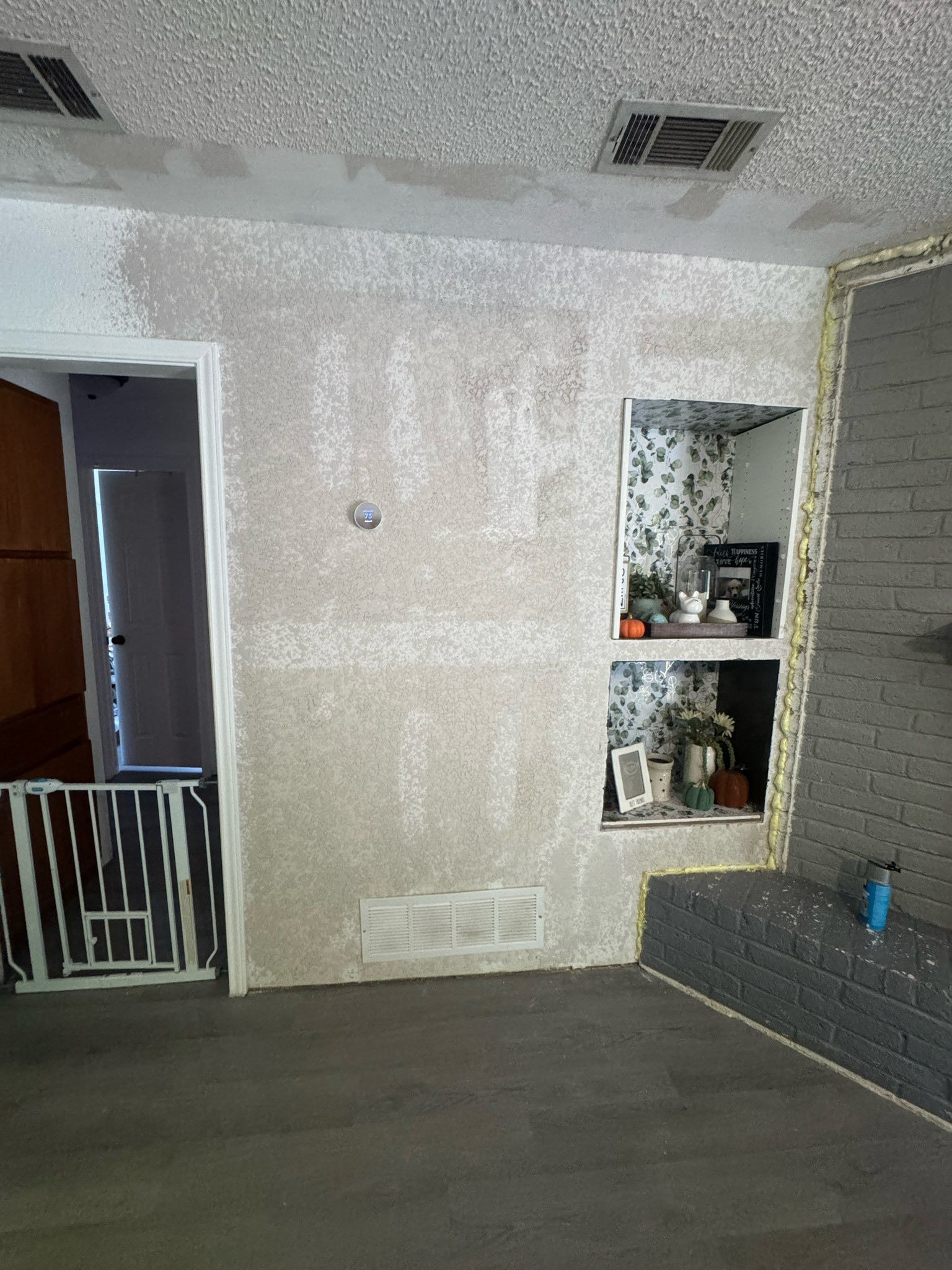 Indoor living room with a textured wall, doorway, window niche, and gray couch under a white ceiling.