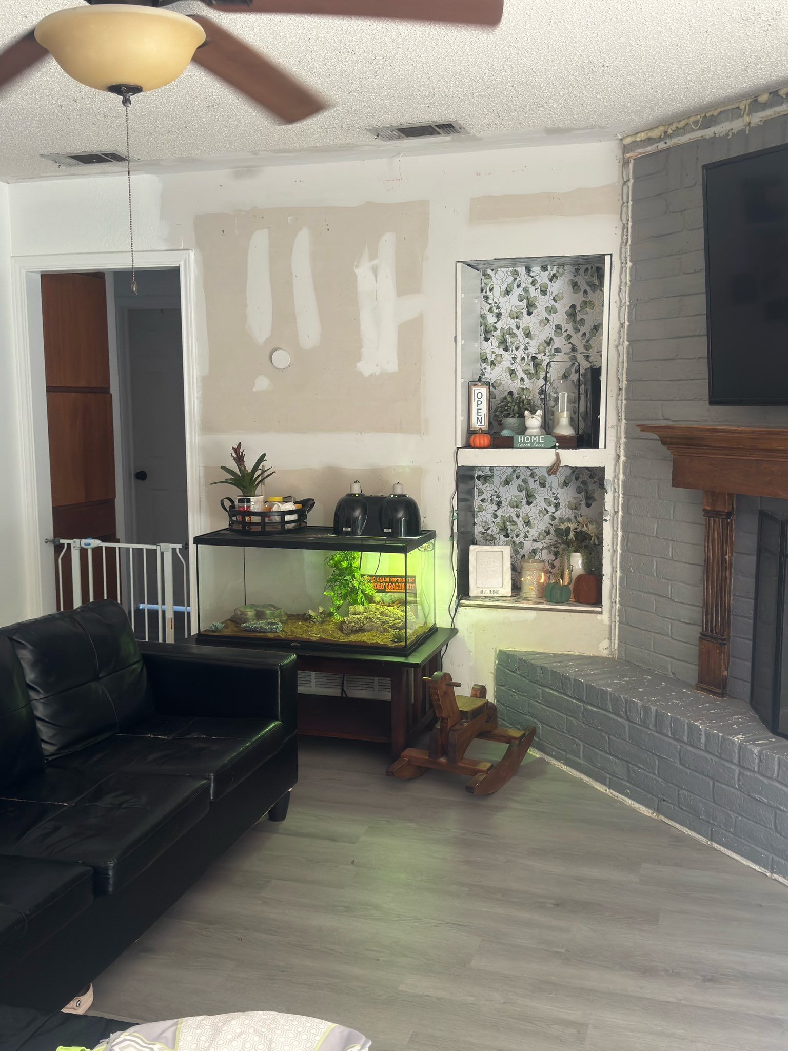 Living room with black sofa, lit aquarium, fireplace, and wall-mounted TV