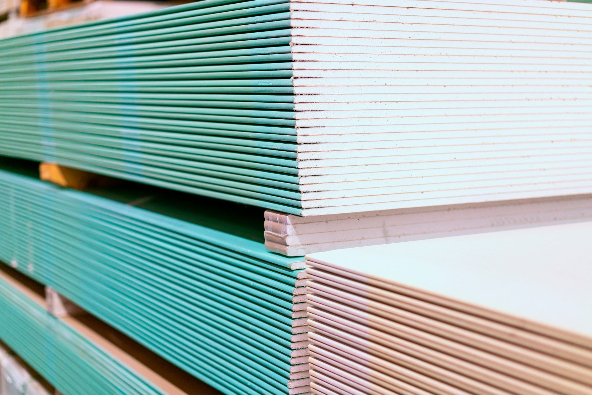 Stacks of green and pink drywall sheets on a warehouse rack