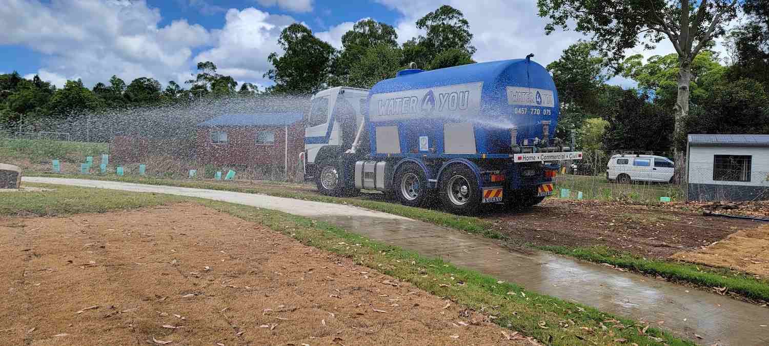 A Large Blue Truck is Spraying Water on a Dirt Road — Water 4 You In Clovass, NSW