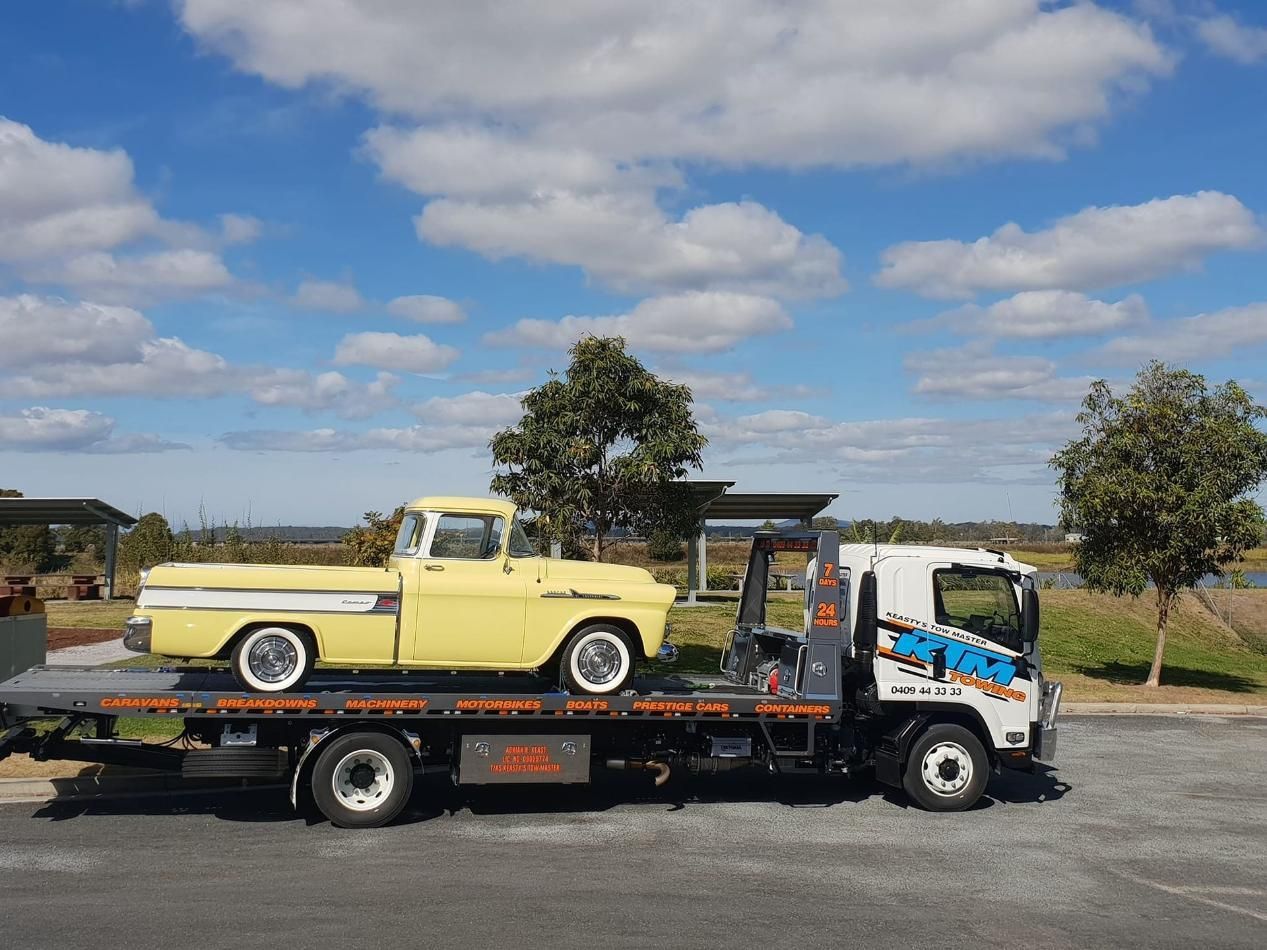 A Yellow Truck Is Being Towed By A Tow Truck — KTM Towing In Macksville, NSW