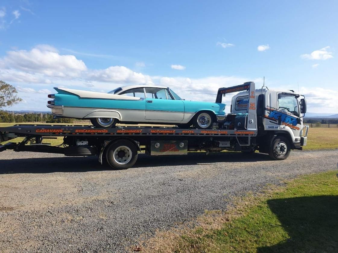 A Blue And White Car Is Being Towed By A Tow Truck — KTM Towing In Macksville, NSW
