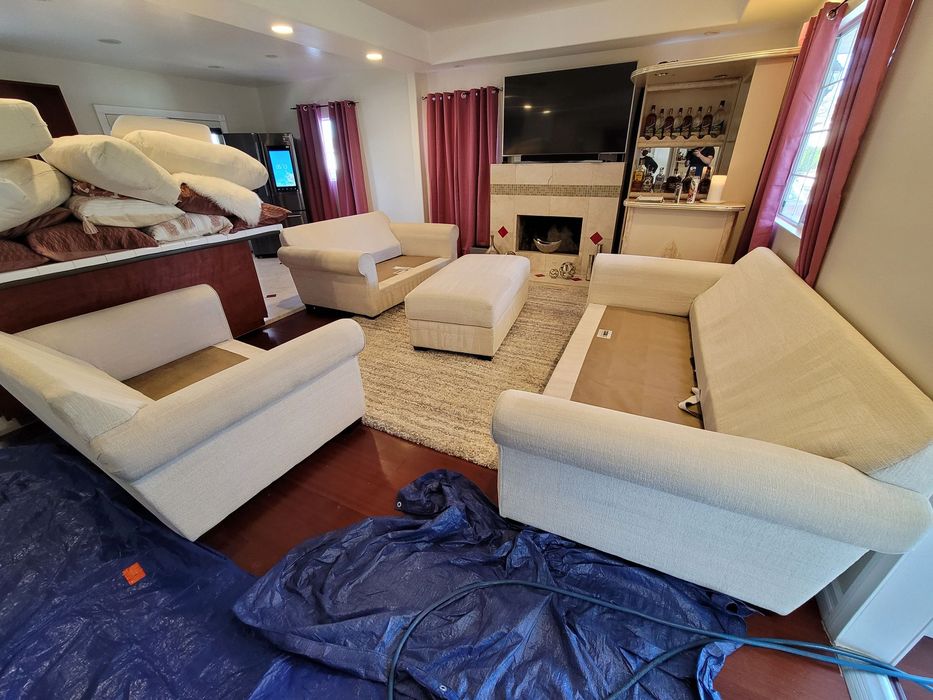 Living room with beige sofas, armchairs, fireplace, TV, and red curtains around a shag rug