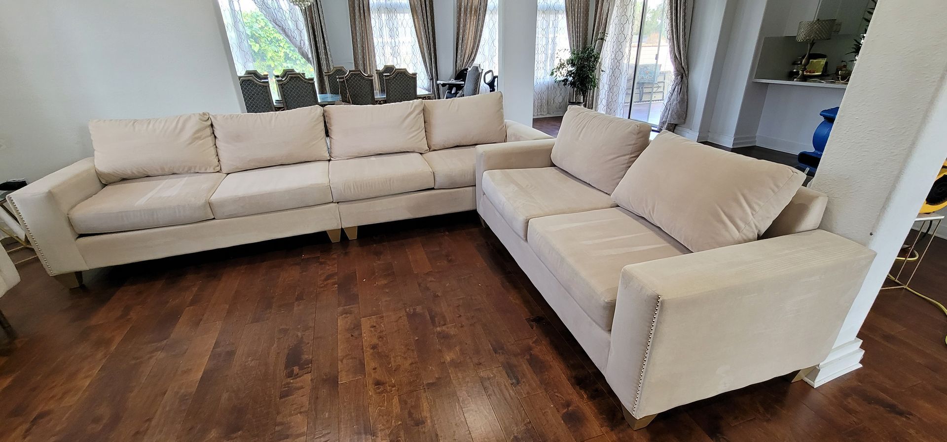 Modern living room with beige sectional sofas around a dark wood floor and large windows