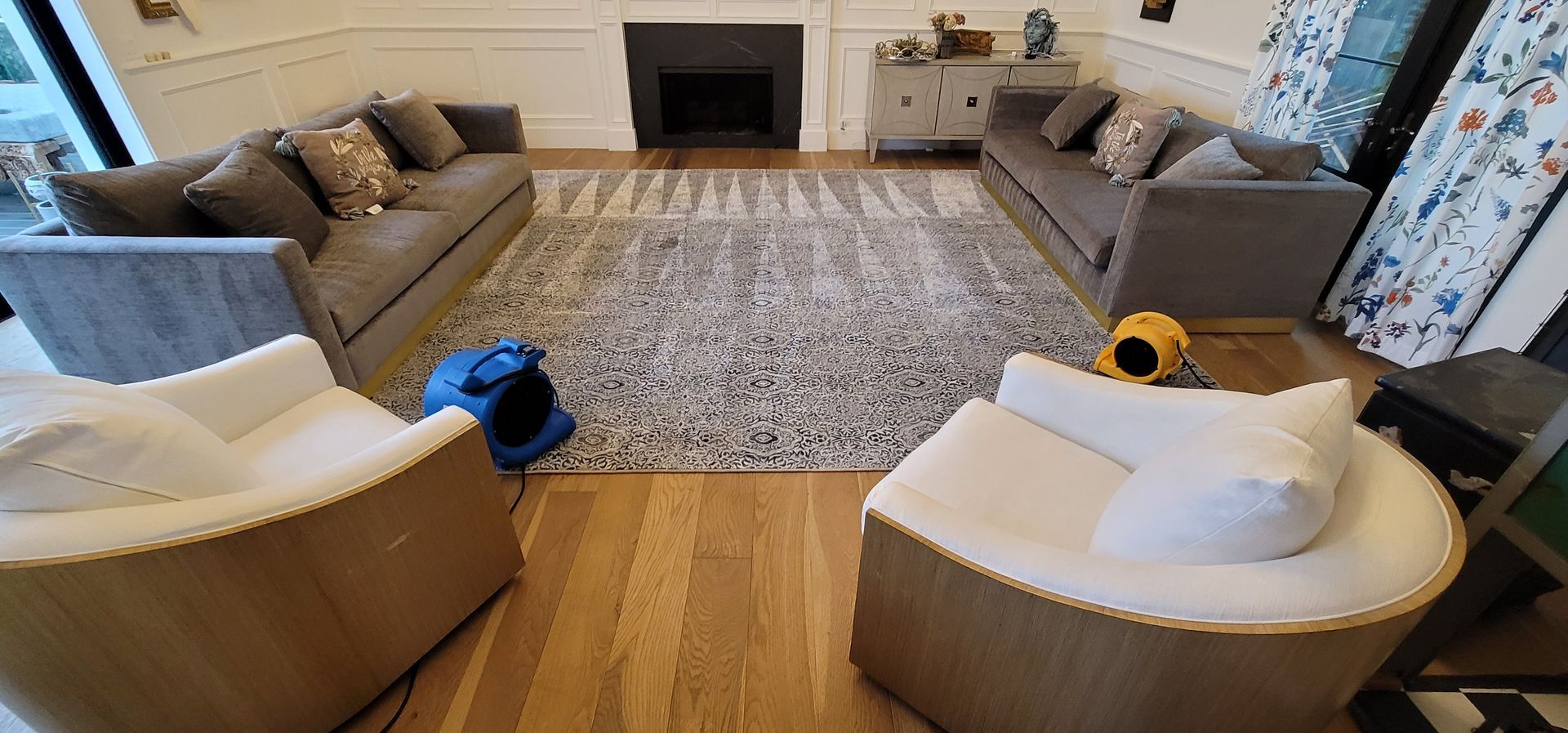 Cozy living room with beige sofas, two white chairs, a patterned rug, and a fireplace.