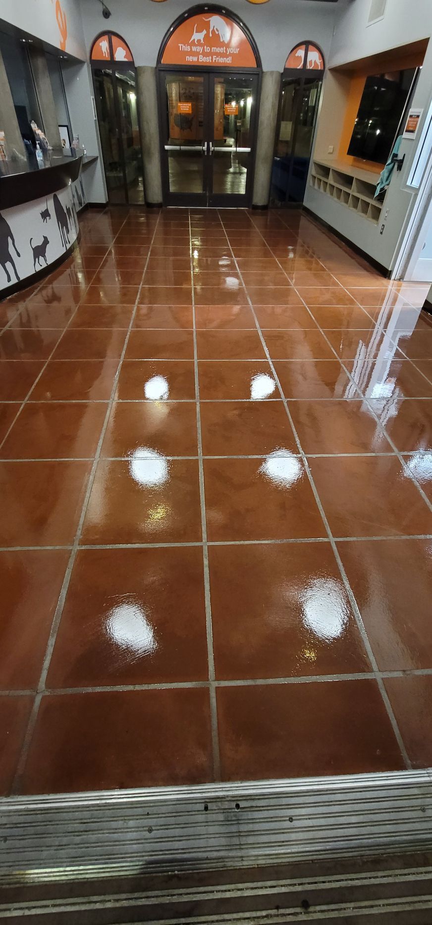 Glossy terracotta-tiled hallway with arched doorways and a storefront at the end.