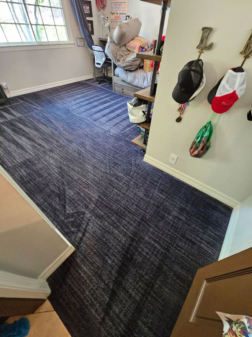 Carpeted entryway with coats and bags hanging by the door, and a window letting in daylight.