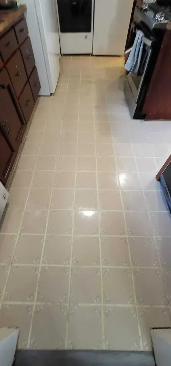 Narrow kitchen hallway with beige tile floor and cabinets on both sides