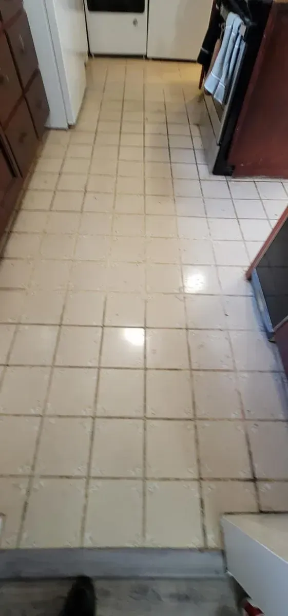 Narrow kitchen hallway with beige tile floor and cabinets along both sides