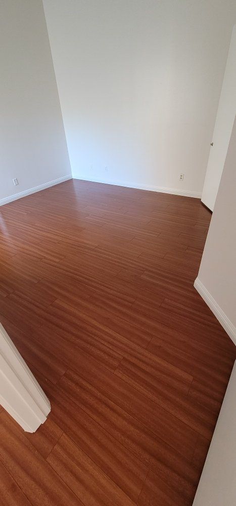 Empty small room with white walls and wood flooring, viewed from a doorway.