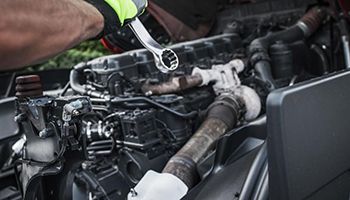 A man is working on a truck engine with a wrench.