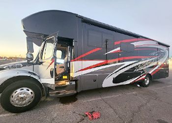 a large black and red rv is parked in a parking lot .