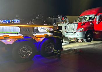 a man is standing next to a tow truck .