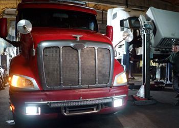 a man is working on a red truck in a garage .