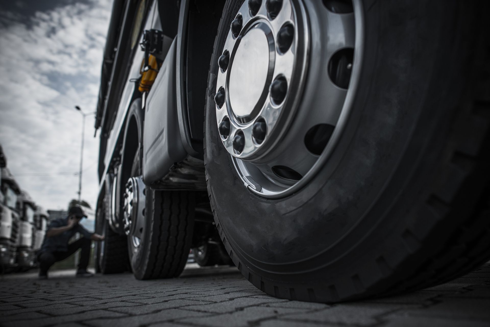 A man is working on the tires of a semi truck.