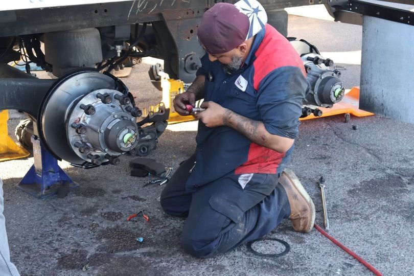 A man is kneeling down working on a truck