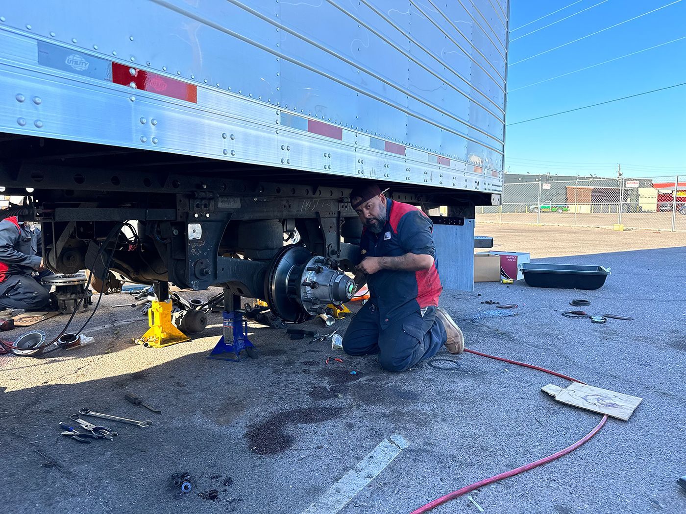 A man is working on the underside of a semi truck.